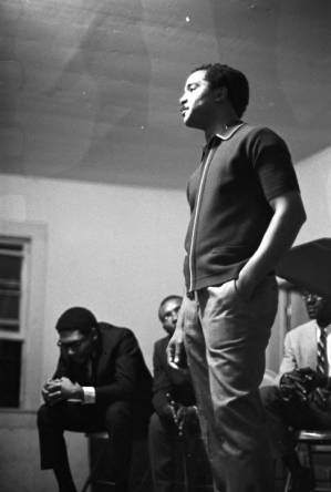 Norman Lumpkin, news director for WRMA radio, speaking on a small stage before a group of people.