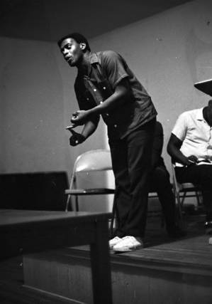 Latt Martin speaking on a small stage before a group of people.