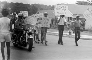 Small group of marchers carrying NAACP signs and marching through a neighborhood.