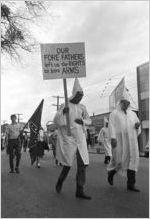 Klansmen and other marchers carrying signs and a Confederate flag in a parade during a Ku Klux Klan rally in Montgomery, Alabama.