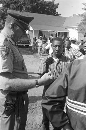 Mississippi Highway Patrol officers speaking to participants in the "March Against Fear" begun by James Meredith, at a rest stop in front of the Century Funeral Home.