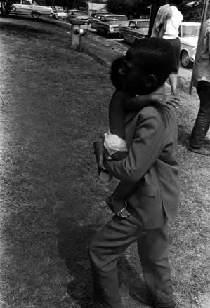 Man carrying a baby away from the road during the "March Against Fear" through Mississippi, begun by James Meredith.
