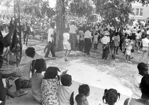 Adults and children seated on a porch, observing the "March Against Fear" through Mississippi, begun by James Meredith.