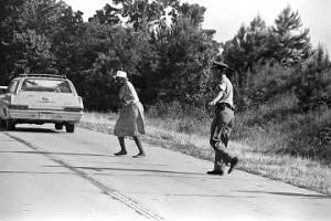 Mississippi Highway Patrol officer stopping traffic to allow an elderly woman to cross the road during the "March Against Fear" begun by James Meredith.