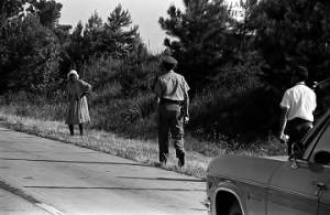 Mississippi Highway Patrol officer walking toward an elderly woman on the side of the road during the "March Against Fear" begun by James Meredith.