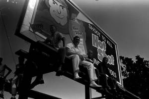 Four white men sitting on the platform in front of a billboard, observing the "March Against Fear" through Mississippi.