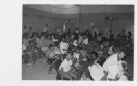 A Group of Men, Women, and Children Seated in a School Gym, circa 1989