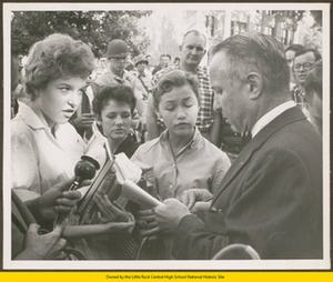 Three white female students talking to reporter