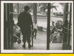 National Guardsman standing inside entry to Central High School with students outside