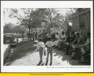Black elementary-aged children walk past white adults near Central High School