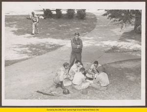 National Guard troops playing cards on lawn in front of Central High School