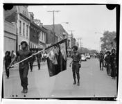 Members of the Black Panthers marching on street, with banner showing fist breaking chains inscribed "Blood"