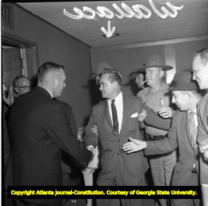 Governor George Wallace surrounded by supporters while demonstrations against him take place outside, 1963