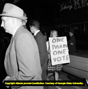 Demonstrators hold signs with 'One Man, One Vote' while Gov. George Wallace visits Atlanta, 1963