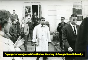 Hamilton Holmes, one of the first two African-American students to integrate the University of Georgia, leaving a campus building in Athens, Georgia, January 1961. White male students are shown in the background.
