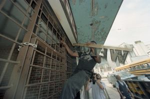 Volunteer, Rodney Johnson, removing a welcome sign from the barred entrance to the Imperial Hotel, where the city's homeless had been living for two weeks, Atlanta, Georgia, July 3, 1990.