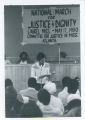 United League poet reads to group in front of banner for "National March for Justice & Dignity"