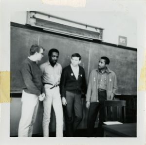 Four men standing at the front of a classroom