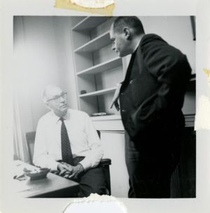 Two men speak in an office