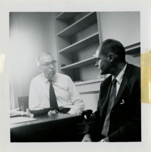 Two men speak in an office