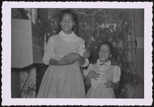 [Portrait of two girls standing in front of a Christmas tree, holding dolls] [graphic].