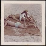 [Teenagers lying on a blanket on the beach] [graphic].