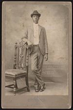 [Unidentified young man, full-length portrait, standing, arm resting on chair, facing front] [graphic].
