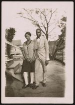 [Couple posing in front of wooden steps] [graphic].