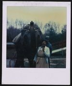[Unidentified woman and man standing next to elephant raising its trunk] [graphic].