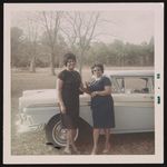 [Two unidentified women, wearing black dresses, posing next to car] [graphic].