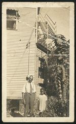 [Unidentified man and girl standing in front of a dwelling with a fire escape] [graphic].
