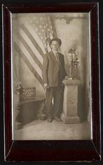 [Unidentified man, standing, full-length in front of United States flag] [graphic].
