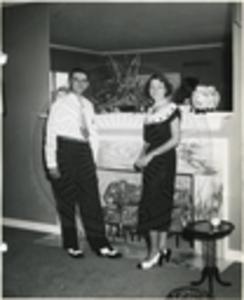 Carroll Gartin standing with [wife] by fireplace