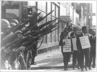 Striking Memphis sanitation workers march by National Guardsmen, 1968