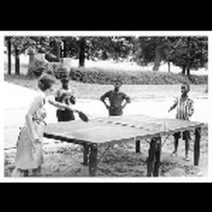 Kathleen Dahl playing ping-pong with three African American boys; undated