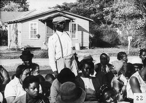 Man Stands Amid Seated Crowd